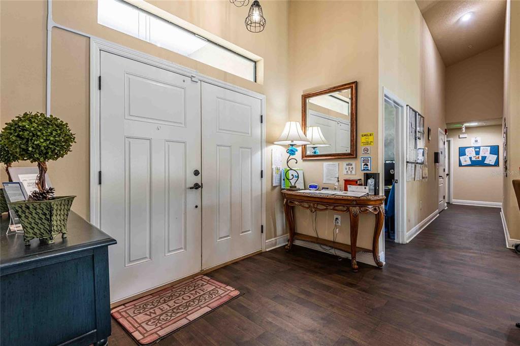 A bright entryway features double white doors, dark wood flooring, and a decorative console table — 13031 PARTRIDGE STREET, SPRING HILL, FL