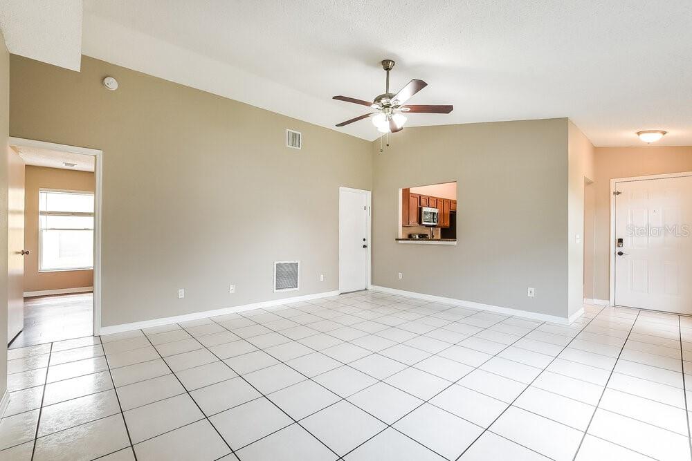 An empty living room features white tile flooring, beige walls, and a ceiling fan — 145 BURNSED PLACE, OVIEDO, FL