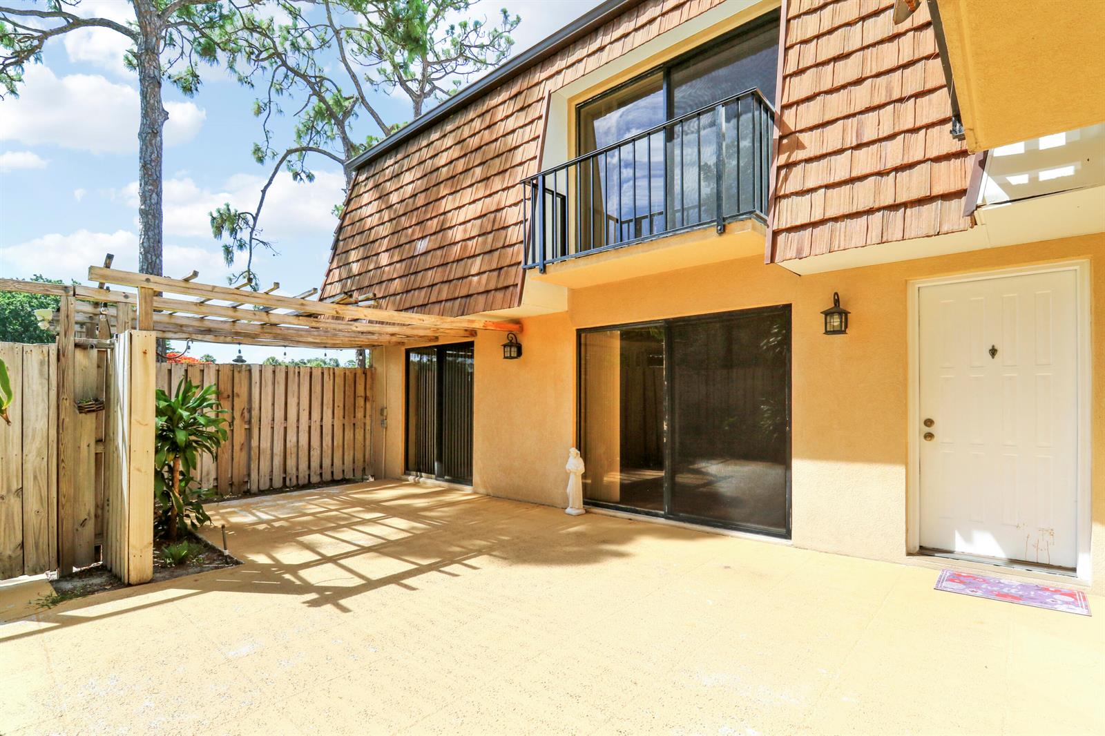 A patio with a wooden pergola sits in front of a two-story house with siding — 1511 15th Lane Bldg 65, FL 33463, FL