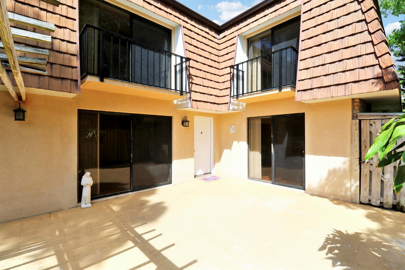 A two-story building exterior features a concrete patio, sliding glass doors, and upper-level balconies — 1511 15th Lane Bldg 65, FL 33463, FL