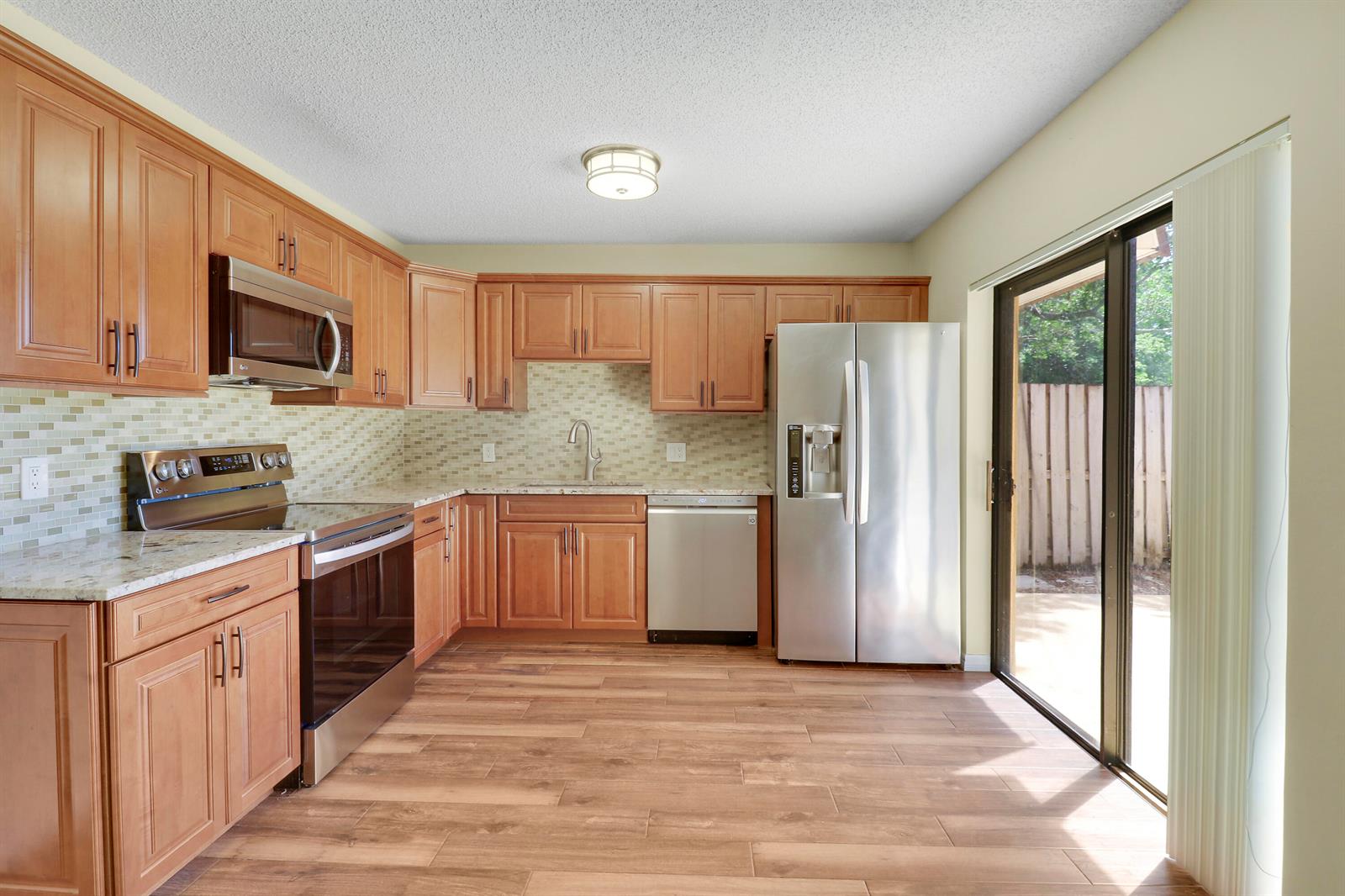 A kitchen with wood cabinets, stainless steel appliances, granite countertops, and a sliding glass door — 1511 15th Lane Bldg 65, FL 33463, FL