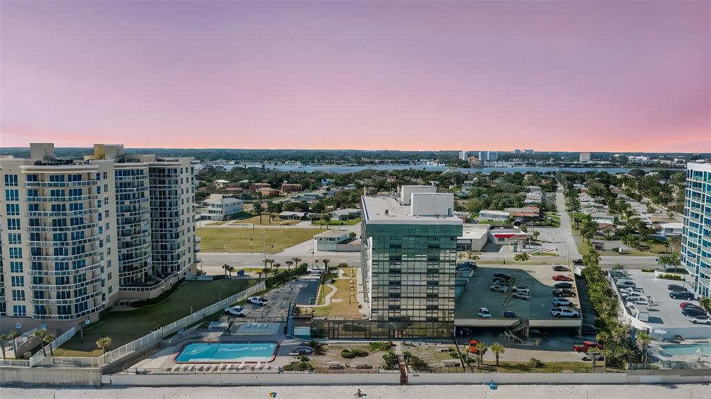 An aerial view shows two high-rise buildings with a swimming pool and parking lots nearby — 1909 S ATLANTIC AVENUE UNIT 717, DAYTONA BEACH, FL