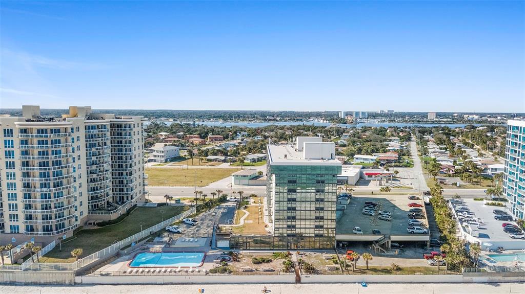 An aerial view shows two high-rise buildings with a swimming pool and parking lot nearby — 1909 S ATLANTIC AVENUE UNIT 717, DAYTONA BEACH, FL