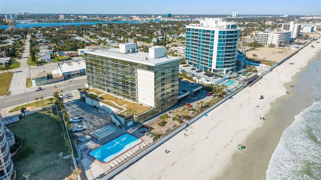An aerial view shows two beachfront high-rise buildings with a swimming pool and parking lot — 1909 S ATLANTIC AVENUE UNIT 717, DAYTONA BEACH, FL