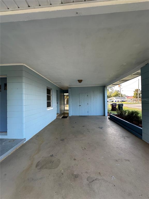 A covered carport with light blue walls, a concrete floor, and a storage closet — 1400 CAROLINA AVENUE, ST CLOUD, FL
