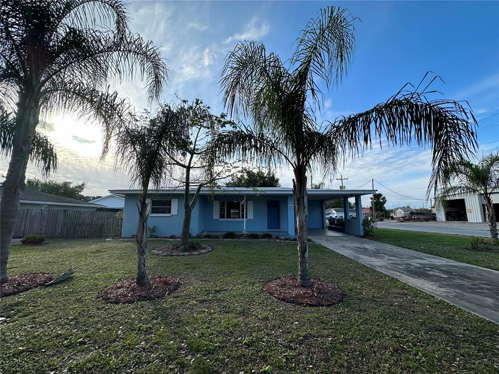 A light blue single-story house features a front porch, a carport, and two palm trees — 1400 CAROLINA AVENUE, ST CLOUD, FL