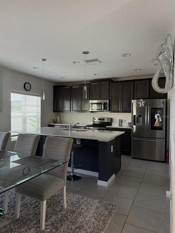 A kitchen features dark wood cabinets, a white quartz island, and stainless steel appliances — 425 TORTUGAS STREET, HAINES CITY, FL