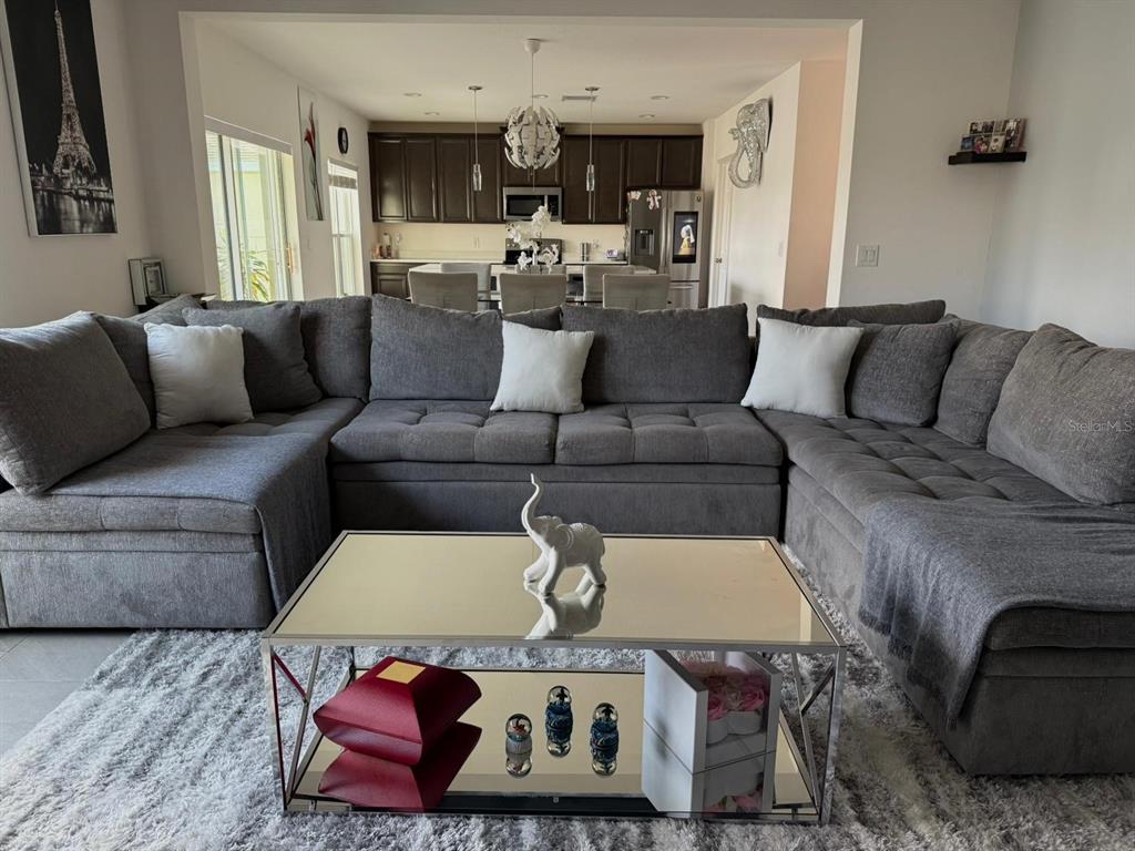 A living room features a large gray sectional sofa, a mirrored coffee table, and an open kitchen — 425 TORTUGAS STREET, HAINES CITY, FL