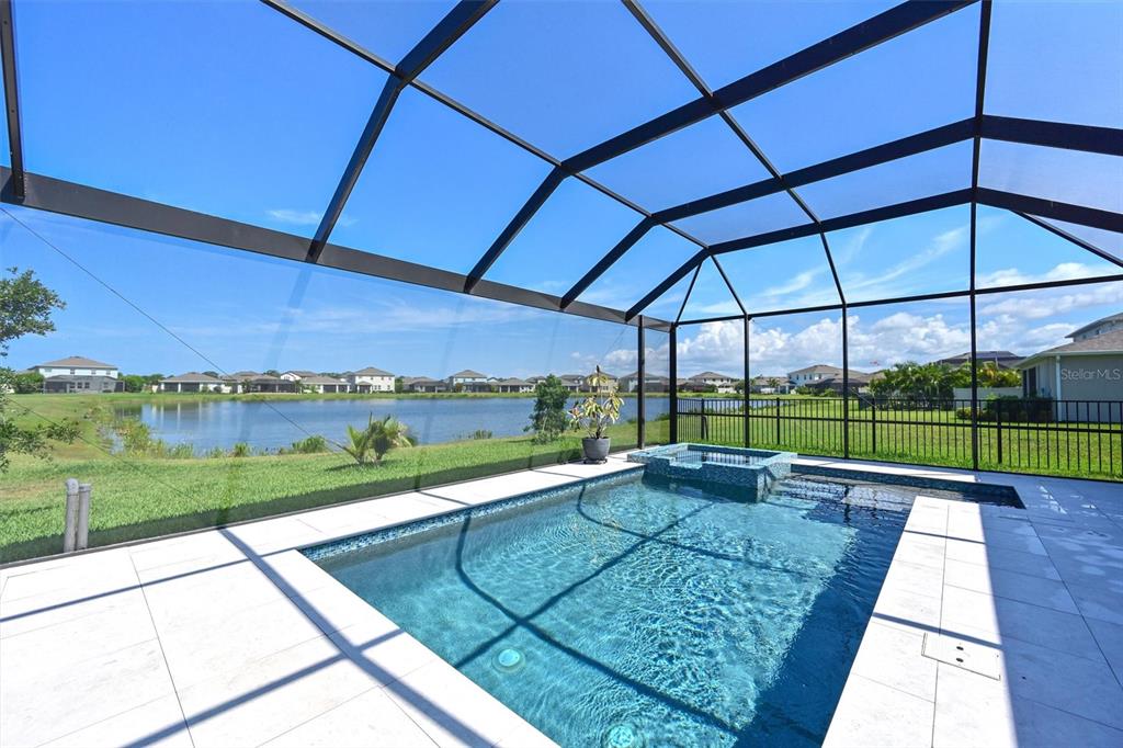 A screened-in pool and spa overlook a lake in a residential neighborhood — 12645 PROMENADE ESTATES BOULEVARD, SARASOTA, FL