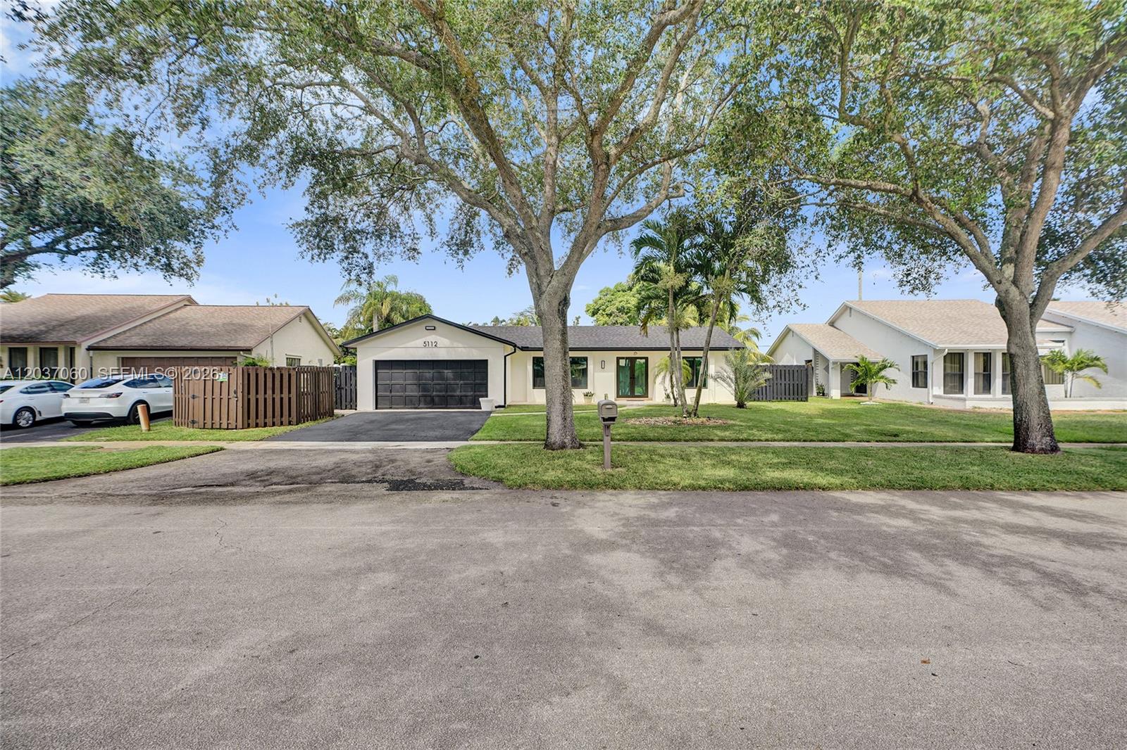 A single-story house with a black garage door and a large tree in the yard — 5112 SW 87th Ave, Cooper City FL 33328, COOPER CITY, FL