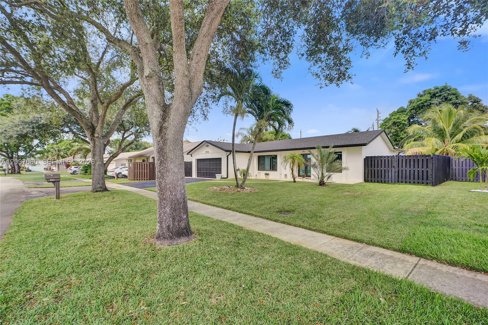 A single-story house with a white exterior, dark roof, and a fenced front yard — 5112 SW 87th Ave, Cooper City FL 33328, COOPER CITY, FL