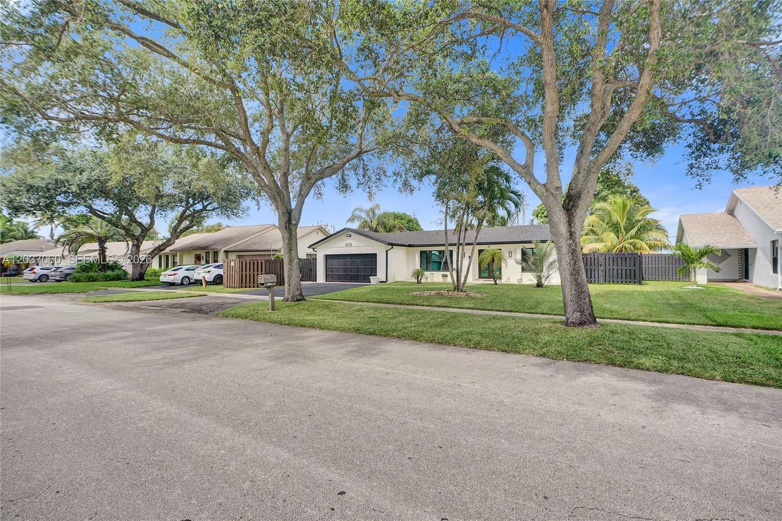 A single-story house with a black garage door and large trees in the front yard — 5112 SW 87th Ave, Cooper City FL 33328, COOPER CITY, FL