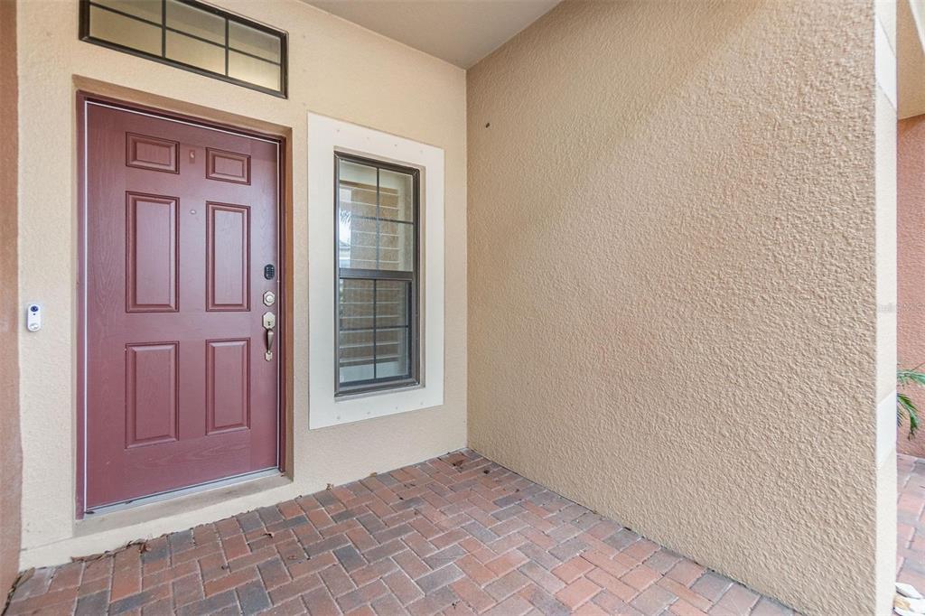 A front entryway features a red door, a window, and brick pavers on the porch — 1958 MILKWEED TRACE, LUTZ, FL