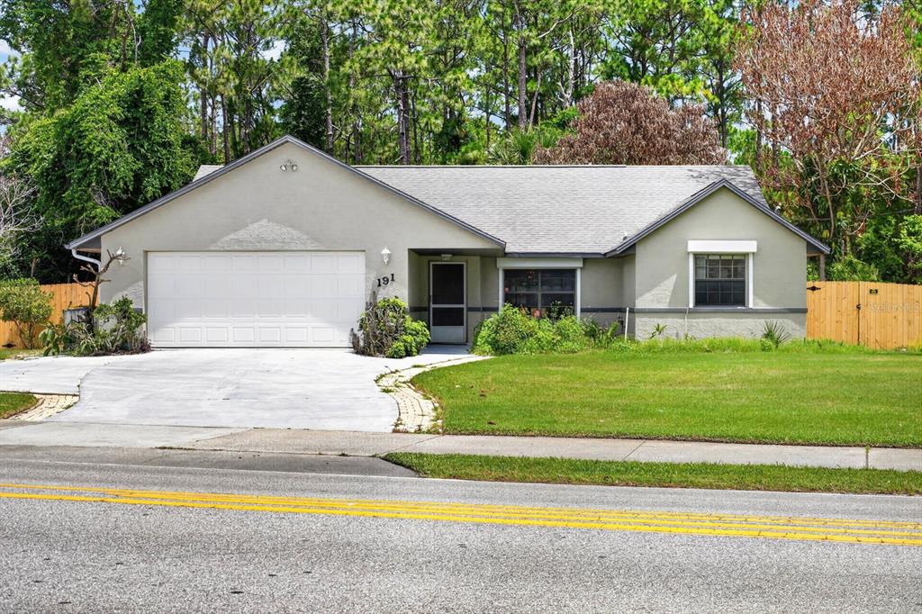 A single-story house with a white garage door, light-colored stucco siding, and a gray roof — 191 ROBERTS ROAD, EDGEWATER, FL