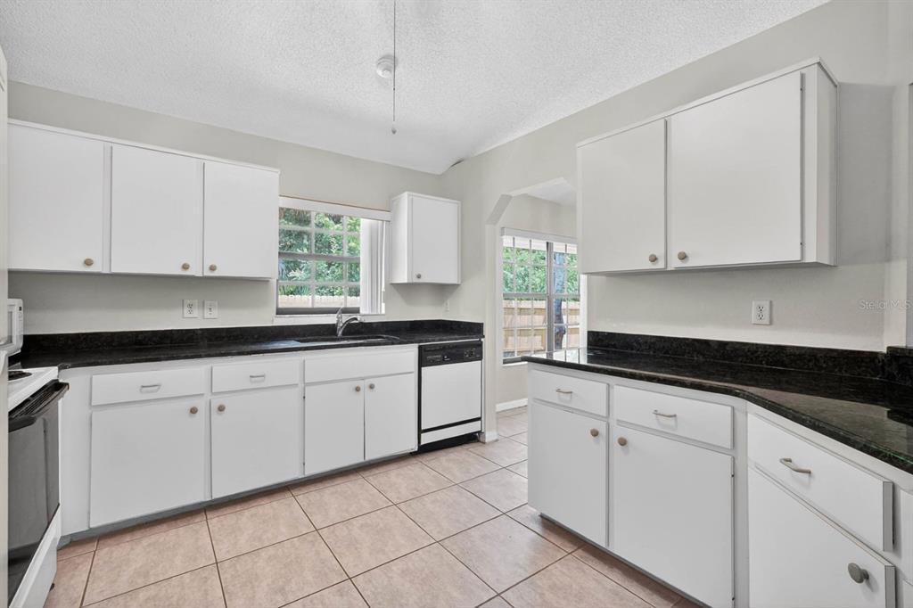 A kitchen with white cabinets, dark countertops, tile flooring, and a window over the sink — 191 ROBERTS ROAD, EDGEWATER, FL