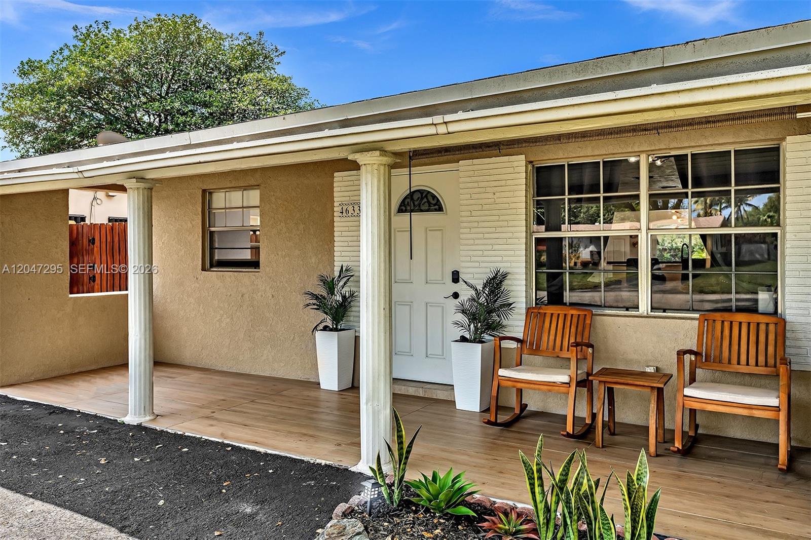 A covered front porch features wood-look flooring, two rocking chairs, and white columns — 4633 SW 28th Ave, Dania Beach FL 33312, DANIA BEACH, FL