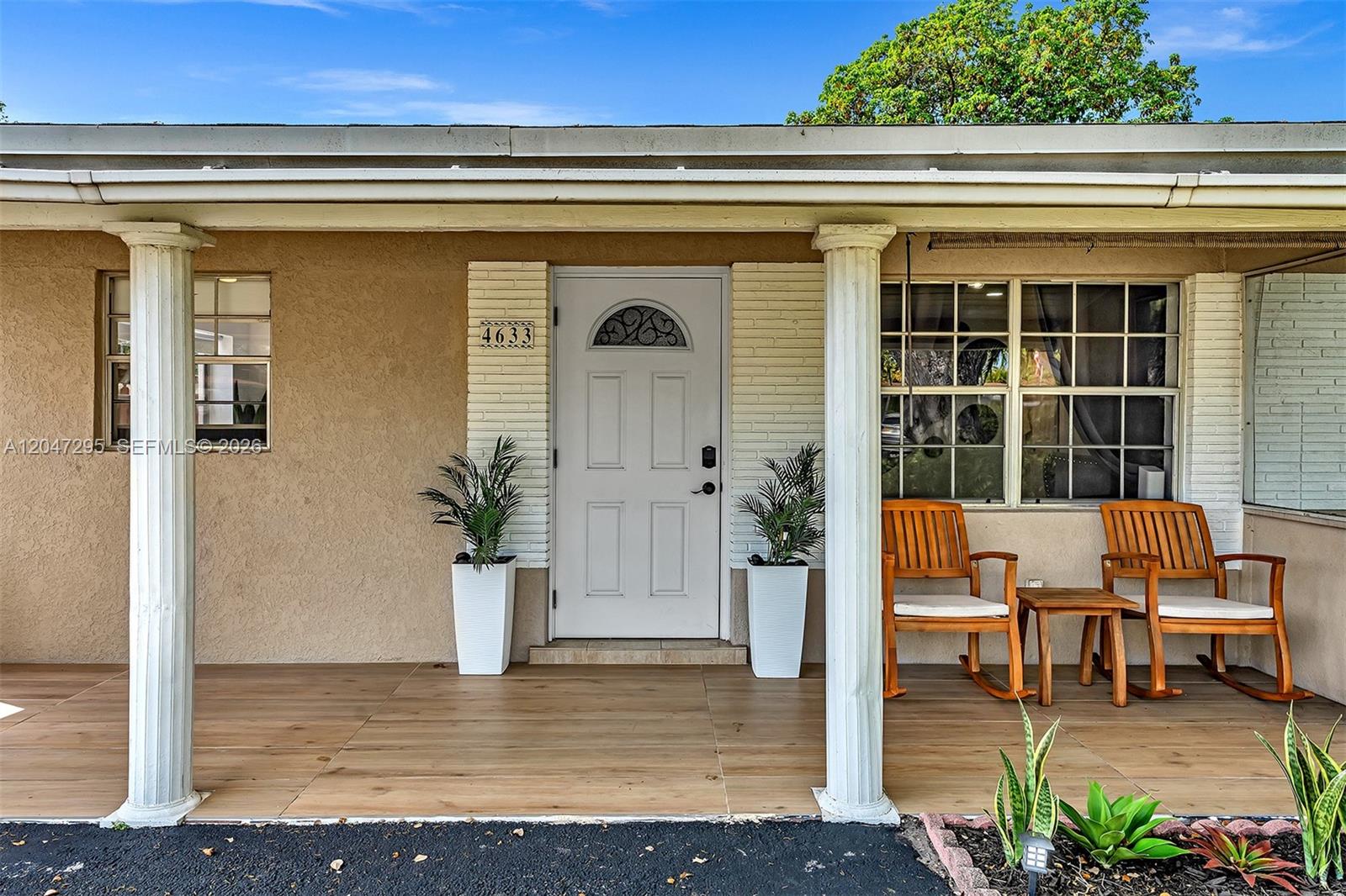 A covered front porch features wood-look tile flooring, two white columns, and two rocking chairs — 4633 SW 28th Ave, Dania Beach FL 33312, DANIA BEACH, FL