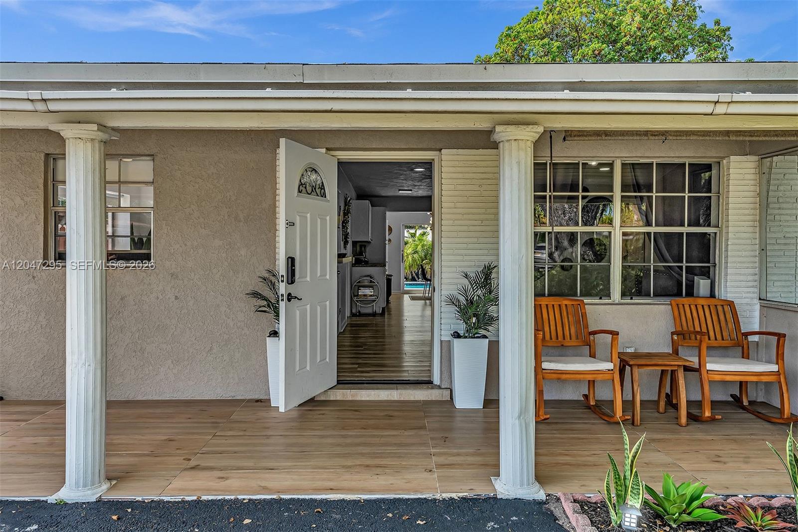 The front porch features two rocking chairs, white columns, and a view into the home — 4633 SW 28th Ave, Dania Beach FL 33312, DANIA BEACH, FL