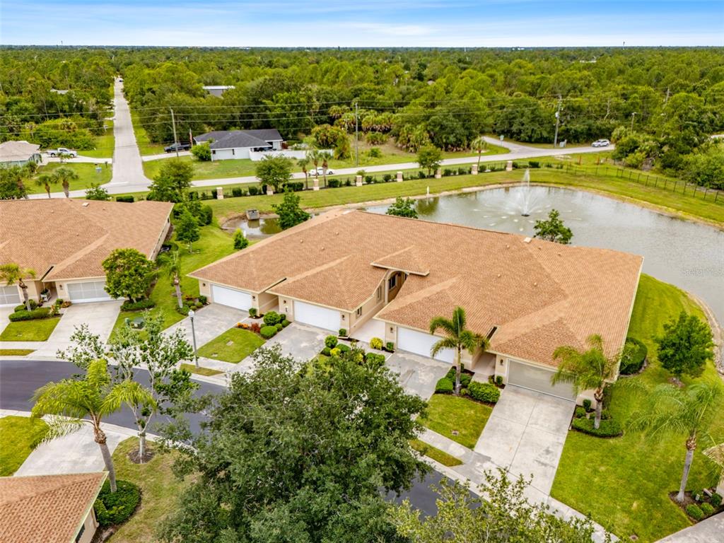 An aerial view shows a multi-unit residential building with tan roofs next to a pond — 24120 GREEN HERON DRIVE UNIT 6, PUNTA GORDA, FL