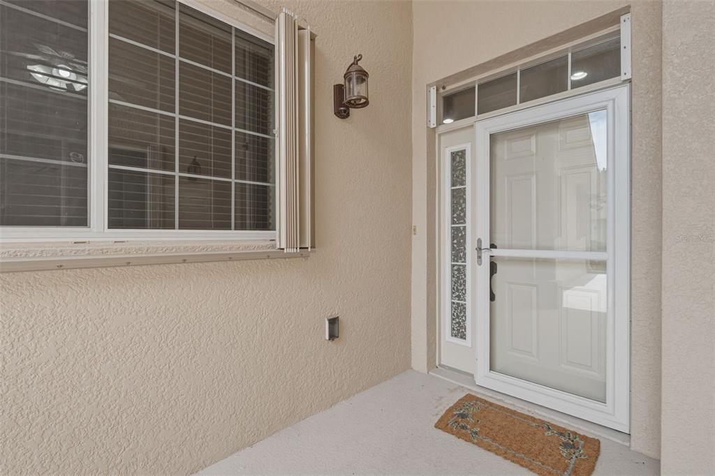A beige exterior entryway features a white front door with a storm door and window — 24120 GREEN HERON DRIVE UNIT 6, PUNTA GORDA, FL
