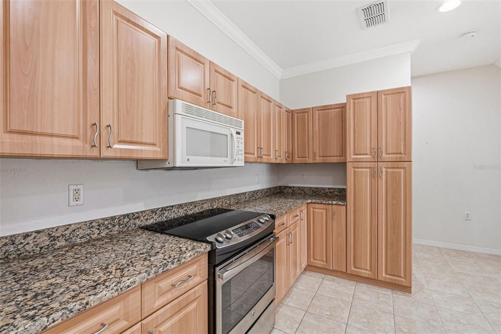 A kitchen features light wood cabinets, granite countertops, and stainless steel appliances — 24120 GREEN HERON DRIVE UNIT 6, PUNTA GORDA, FL