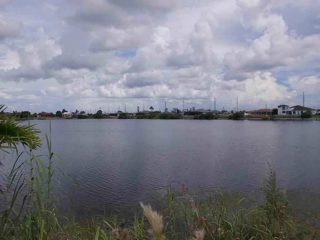 A view of a lake with houses along the distant shoreline under a cloudy sky — 538 NW 25TH TERRACE, CAPE CORAL, FL