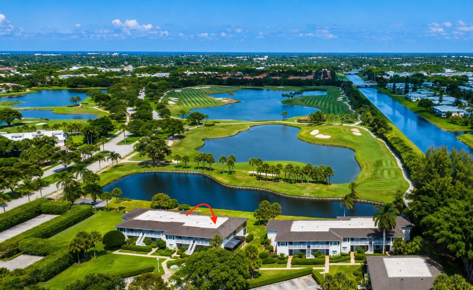 An aerial view of a multi-story apartment building situated next to a golf course and lake — 24 Southport Lane # H, Boynton Beach FL 33436, BOYNTON BEACH, FL