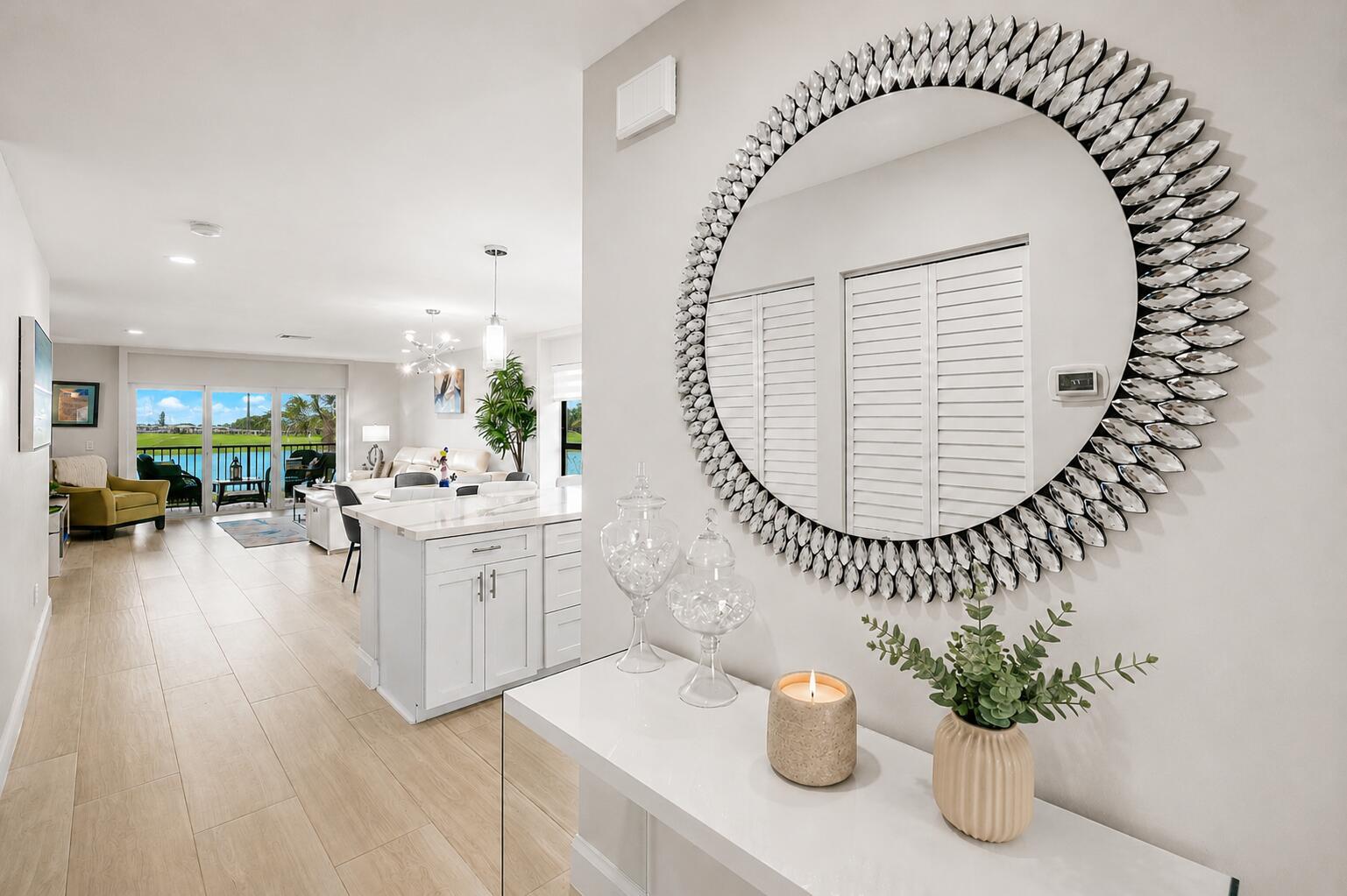 A white console table with a large circular mirror sits in a bright, tiled entryway — 24 Southport Lane # H, Boynton Beach FL 33436, BOYNTON BEACH, FL