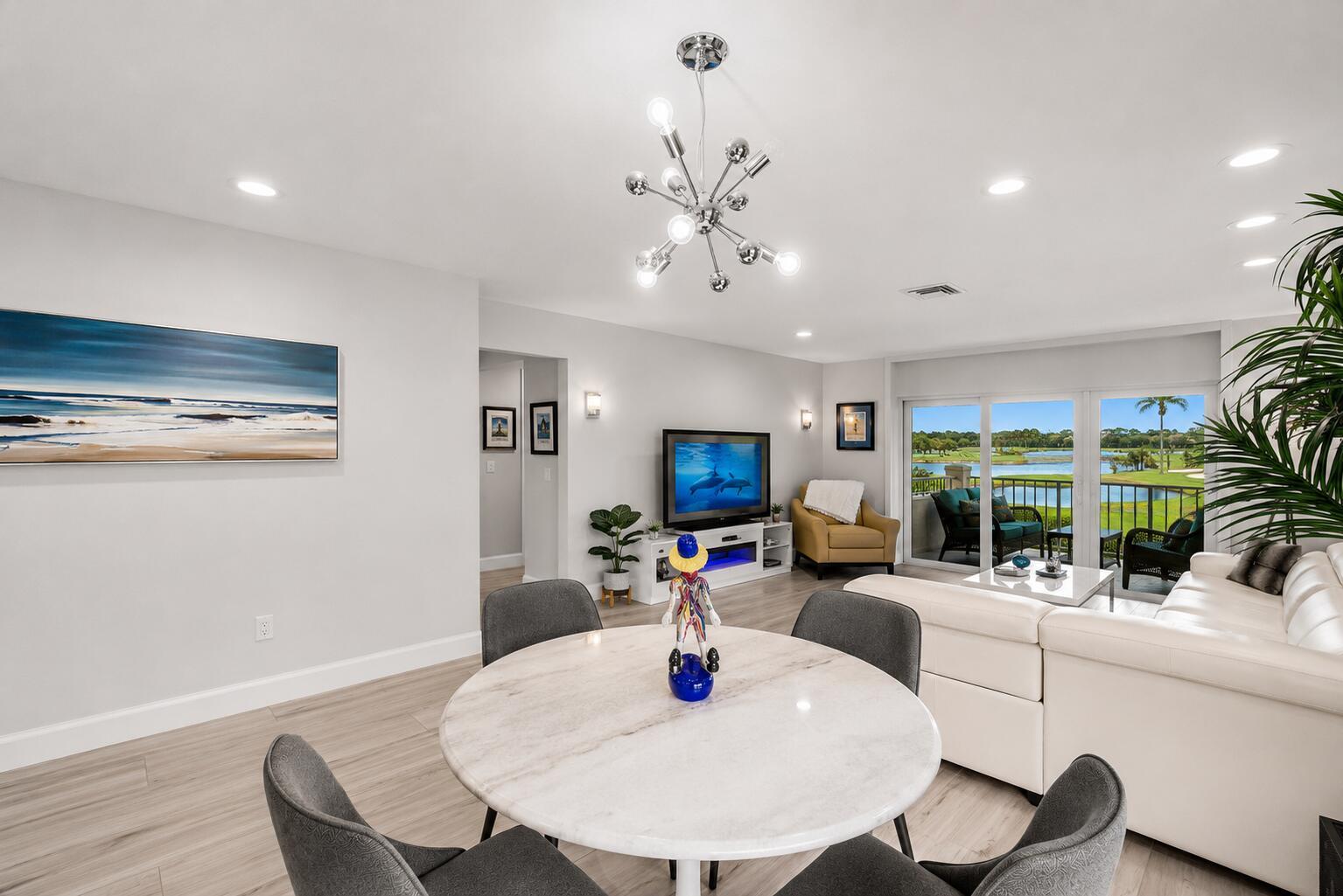A dining area with a round marble table opens into a living room with balcony views — 24 Southport Lane # H, Boynton Beach FL 33436, BOYNTON BEACH, FL