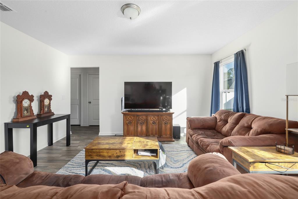A living room features a brown sectional sofa, a wooden coffee table, and a television console — 724 LIBERTY CIRCLE, MACCLENNY, FL