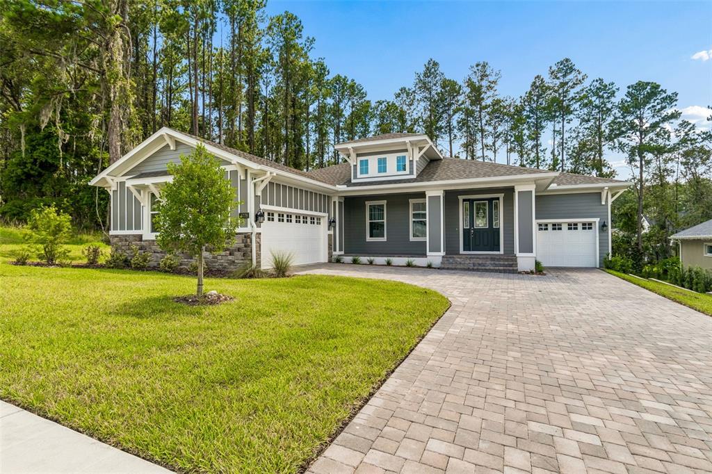 A gray single-story house with a stone base, two garages, and a paved driveway — 4779 MAJESTIC HILLS LOOP, BROOKSVILLE, FL