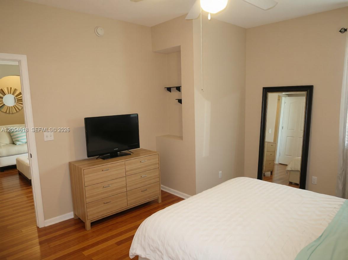 A bedroom features a wooden dresser, a television, a floor mirror, and hardwood floors — 175 Galicia Way # 0, Jupiter FL 33458, JUPITER, FL