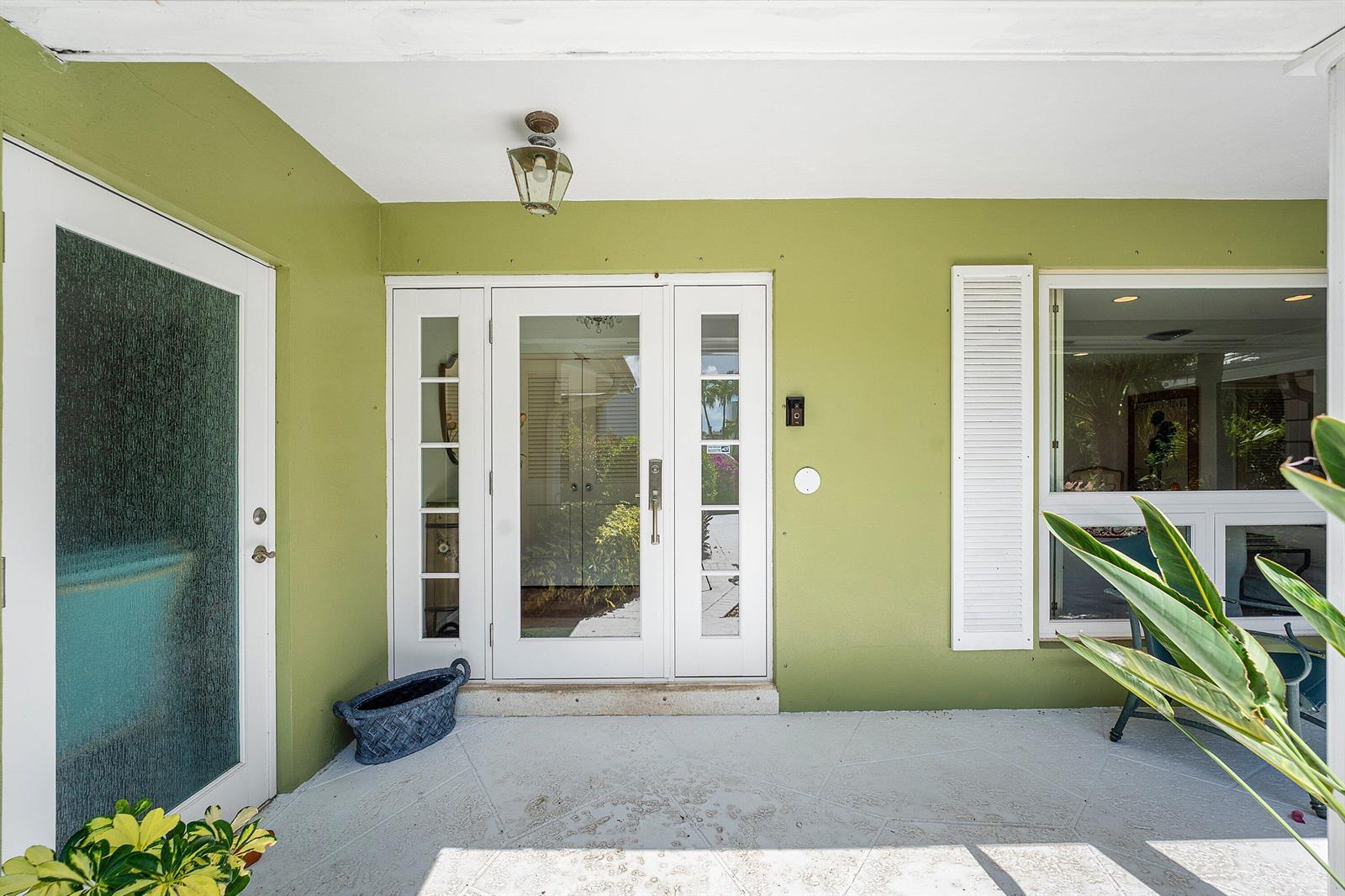 A covered porch features a green wall, a white front door with sidelights, and a window — 1350 Spanish River Road, Boca Raton FL 33432, BOCA RATON, FL