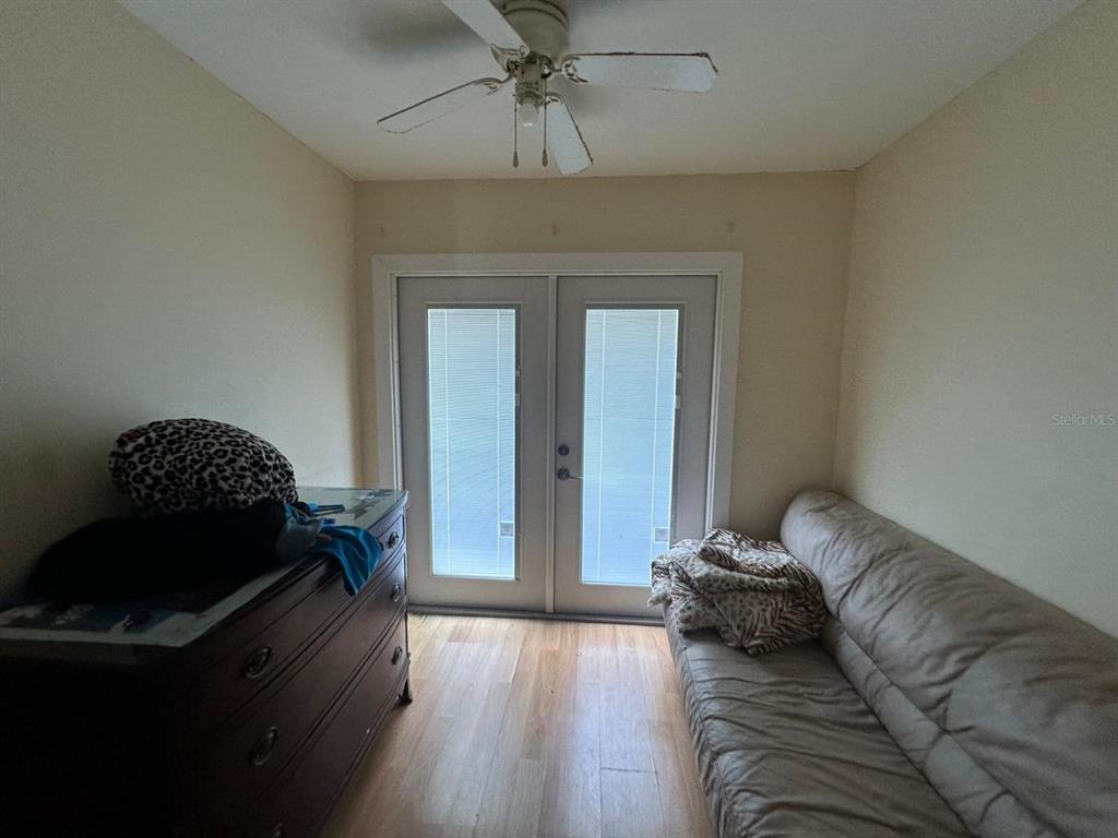 A small room features a ceiling fan, a dresser, a sofa, and double glass doors — 3157 PHLOX DRIVE UNIT 3157, PALM HARBOR, FL