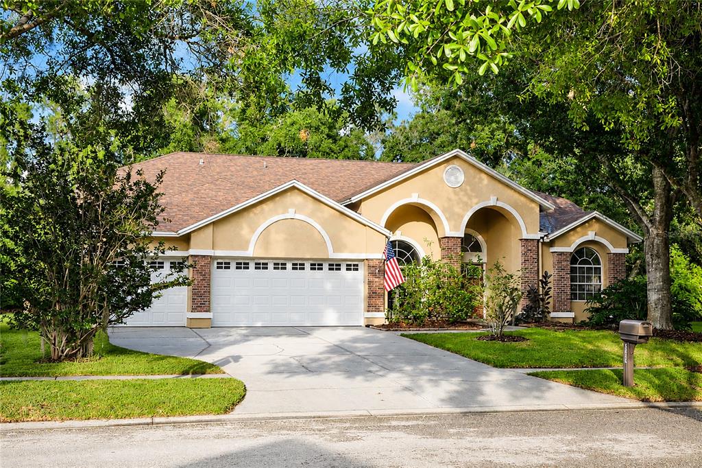 A tan single-story house with a three-car garage, brick accents, and a paved driveway — 5622 GLENCREST BOULEVARD, TAMPA, FL