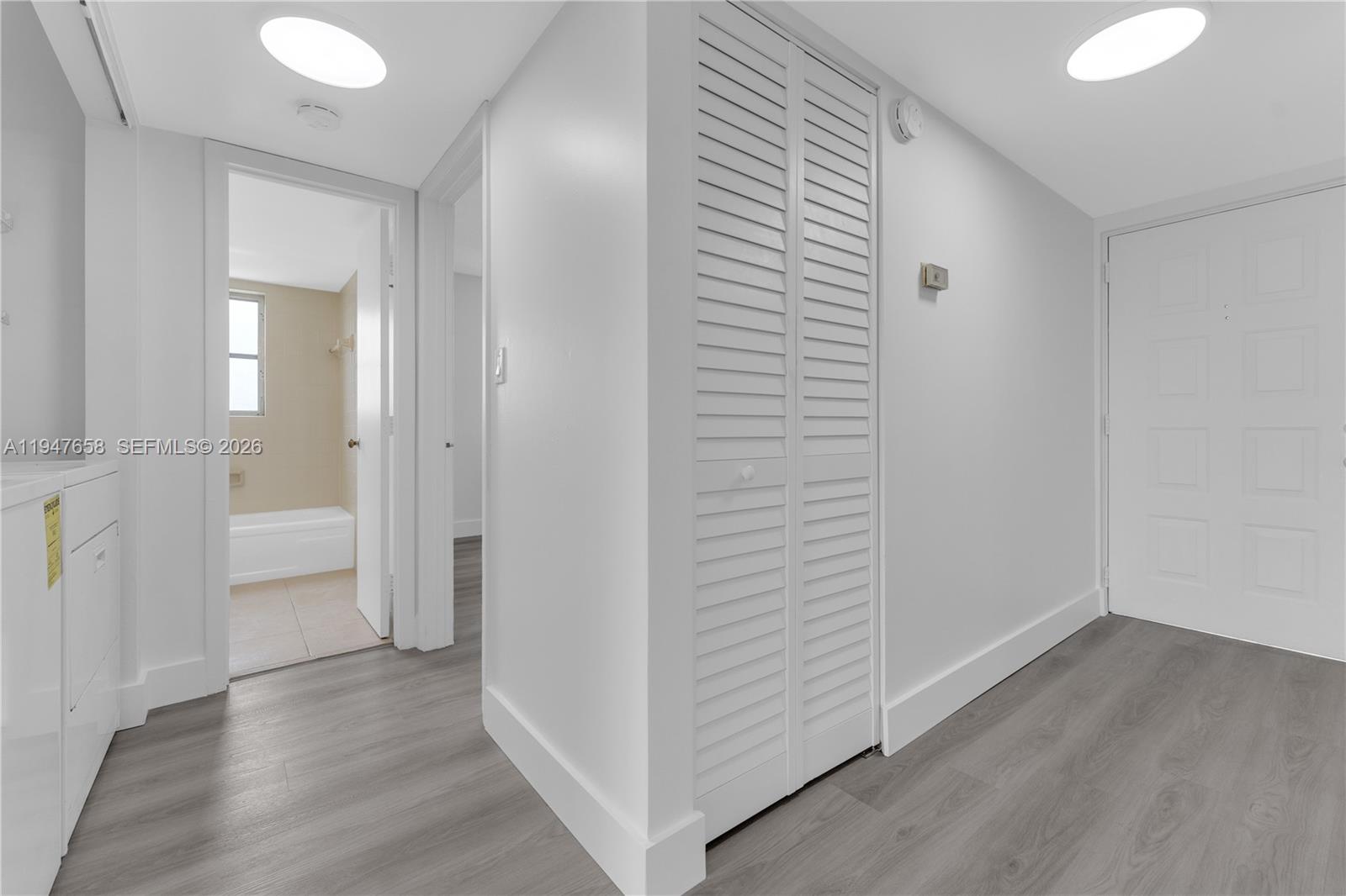 A hallway features white walls, gray wood-look flooring, a louvered closet, and recessed lighting — 8560 N Sherman Cir # 208, Miramar FL 33025, MIRAMAR, FL