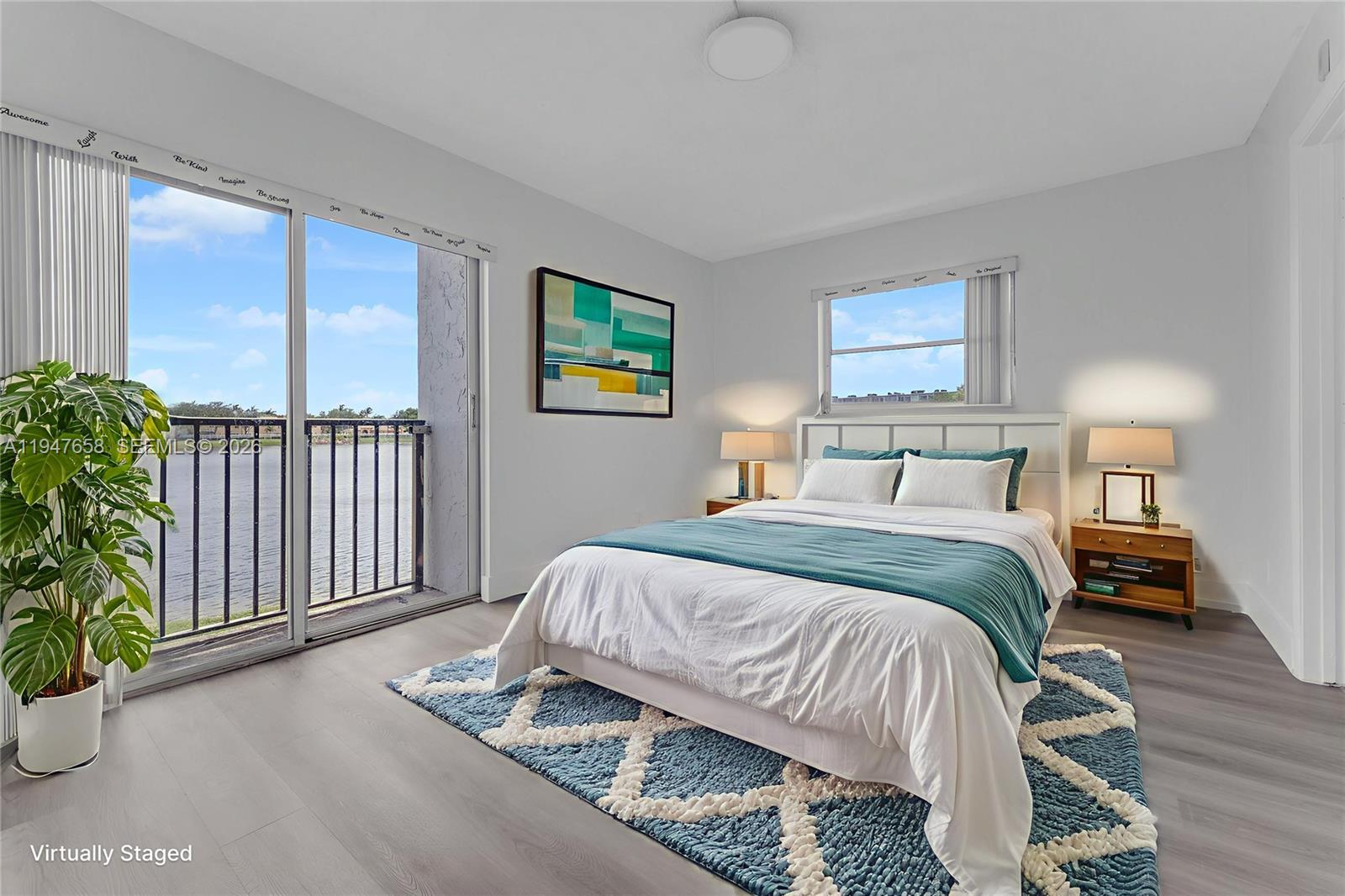 A bedroom features a bed, a blue patterned rug, and a balcony overlooking a lake — 8560 N Sherman Cir # 208, Miramar FL 33025, MIRAMAR, FL
