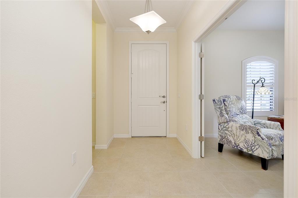 A tiled entryway features a white door, a modern light fixture, and an adjacent room — 228 ACERNO DRIVE, NOKOMIS, FL