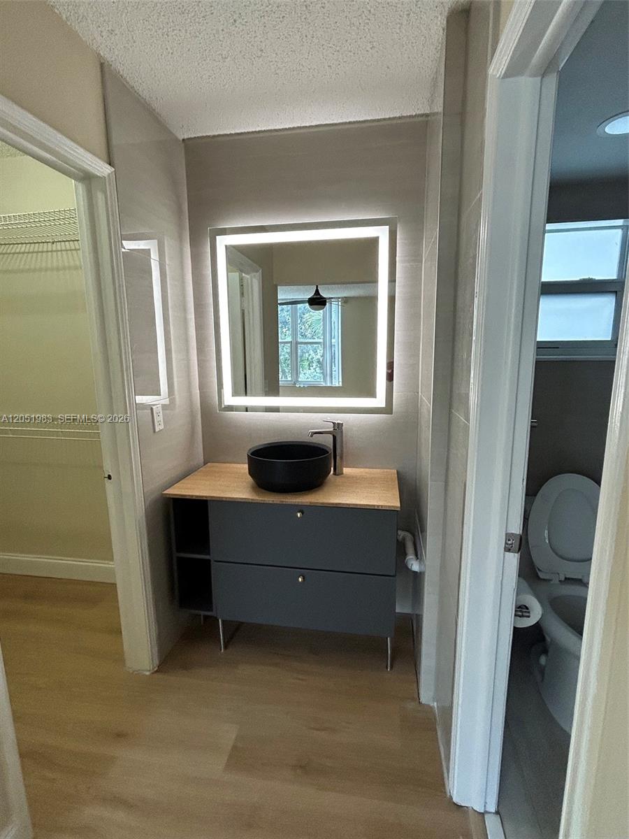 A bathroom vanity area features a black vessel sink, light wood countertop, and LED mirror — 9461 Evergreen Pl # 303, Davie FL 33324, DAVIE, FL