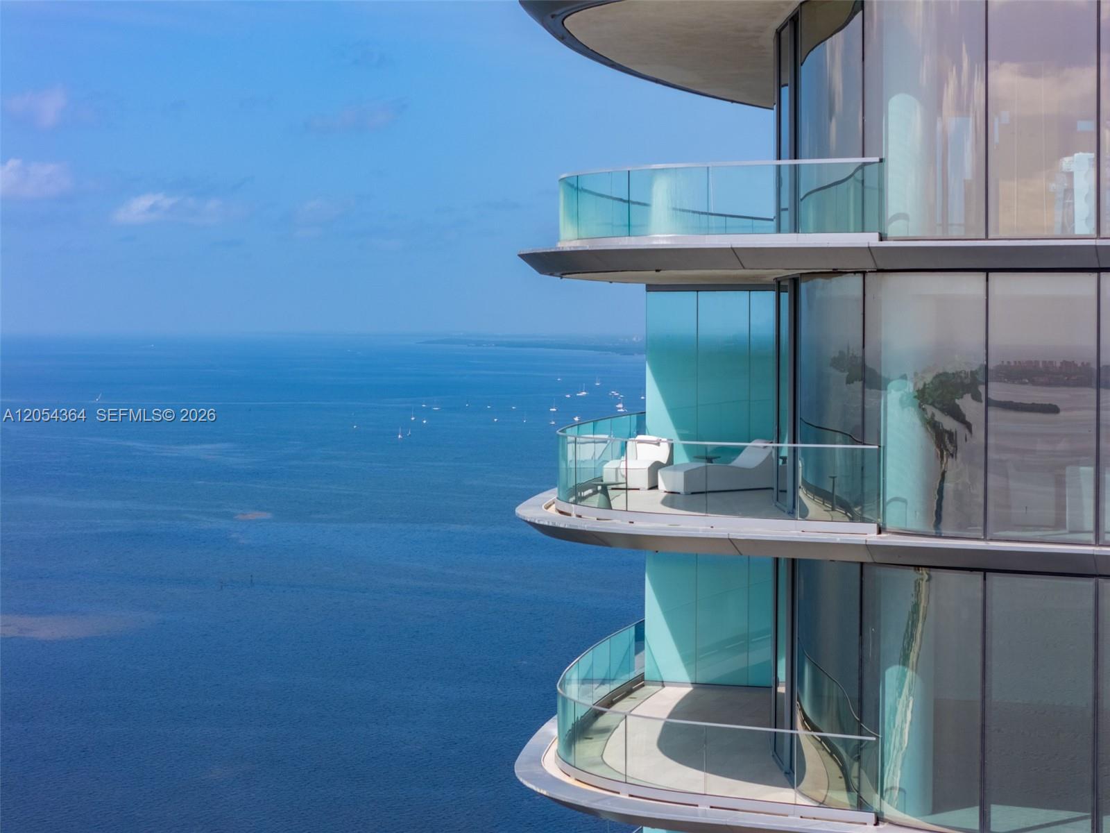 The exterior of a modern high-rise building features curved glass balconies overlooking the ocean — 175 SE 25th Rd # 4001, Miami FL 33129, MIAMI, FL