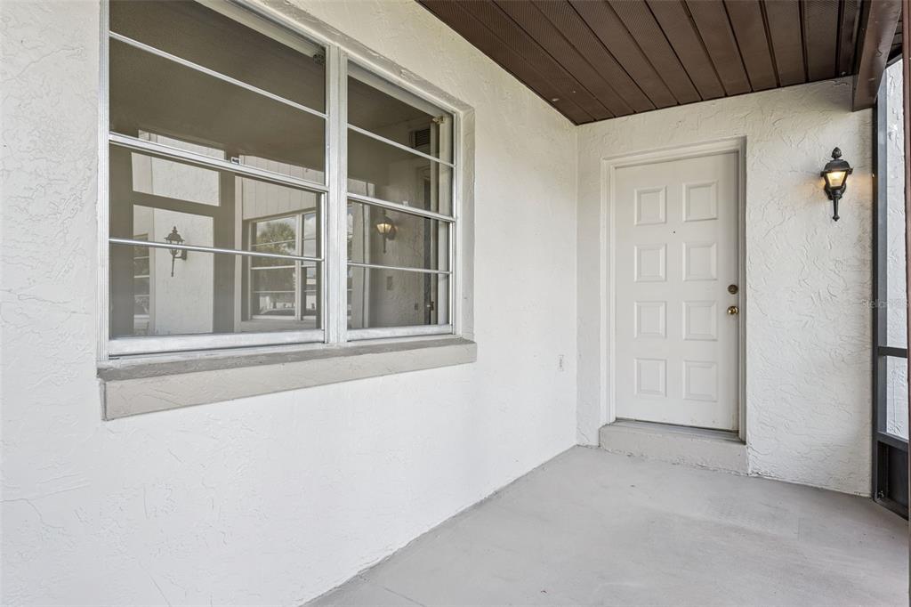 A white front door and a large window are on a covered concrete porch — 93 WINDTREE LANE UNIT 102, WINTER GARDEN, FL