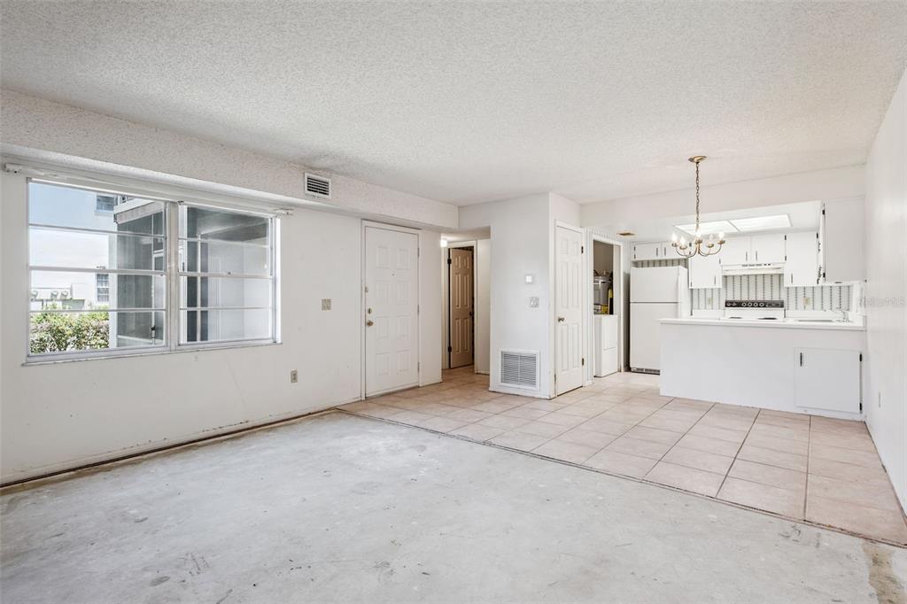An open-concept living area features tile flooring, a white kitchen, and a large window — 93 WINDTREE LANE UNIT 102, WINTER GARDEN, FL