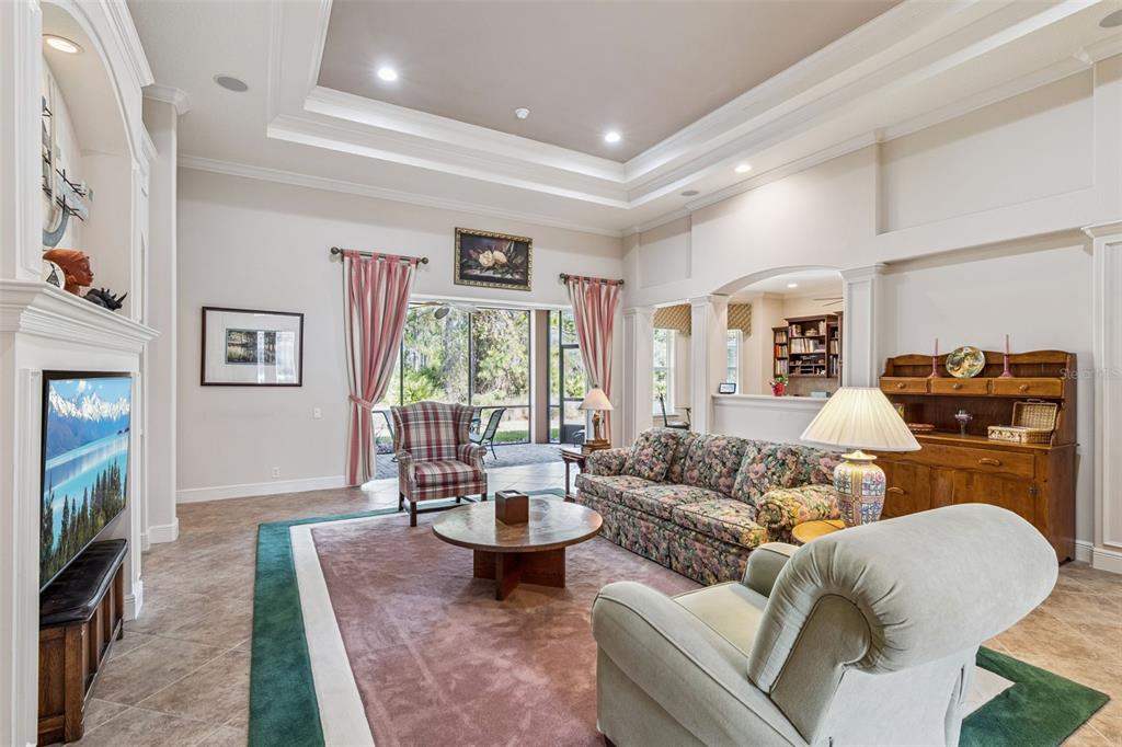 A living room features a fireplace, floral sofa, area rug, and a view of a lanai — 322 BELLINGRATH TERRACE, DELAND, FL