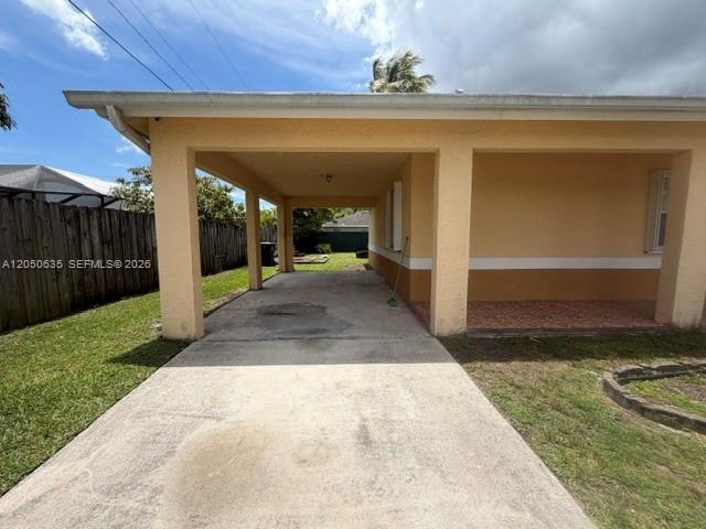 A concrete driveway leads to a covered carport attached to a tan stucco house — 11310 Booker T Washington, Miami FL 33176, MIAMI, FL