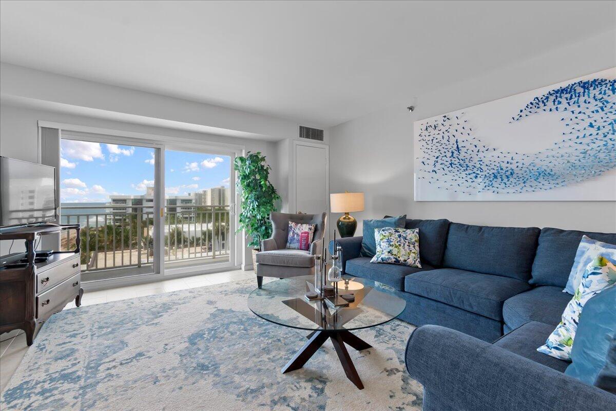 A living room features a blue sofa, glass coffee table, and a balcony overlooking the ocean — 4511 S Ocean Boulevard # 805, Highland Beach FL 33487, HIGHLAND BEACH, FL