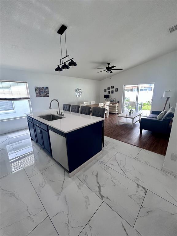 A kitchen with a dark blue island and white countertops opens into a living area — 1061 PORTMOOR WAY, WINTER GARDEN, FL
