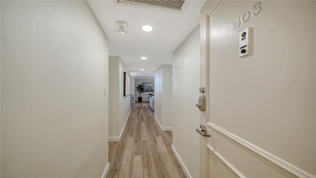 A view from an entryway looking down a hallway with wood-look flooring toward a living area — 1000 LONGBOAT CLUB ROAD UNIT 403, LONGBOAT KEY, FL