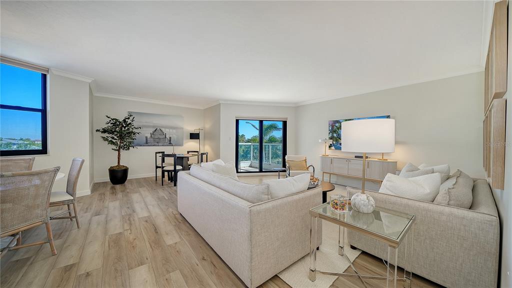 A bright living room features light wood flooring, neutral furniture, and a balcony with palm trees — 1000 LONGBOAT CLUB ROAD UNIT 403, LONGBOAT KEY, FL