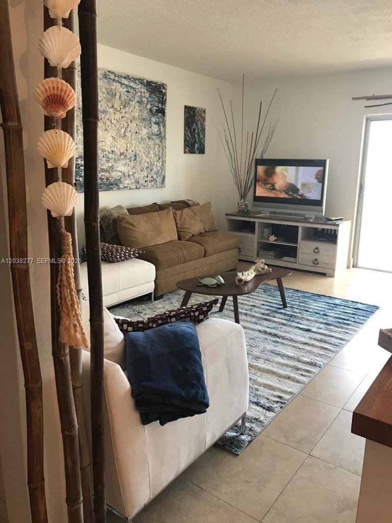A living room features a brown sofa, a white armchair, a television, and a rug — 320 S Surf Rd # 305, Hollywood FL 33019, HOLLYWOOD, FL