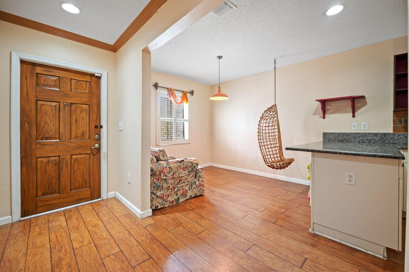 A room with wood-look tile flooring, a hanging wicker chair, and a granite-topped kitchen counter — 2481 NW 98th Lane, Sunrise FL 33322, SUNRISE, FL